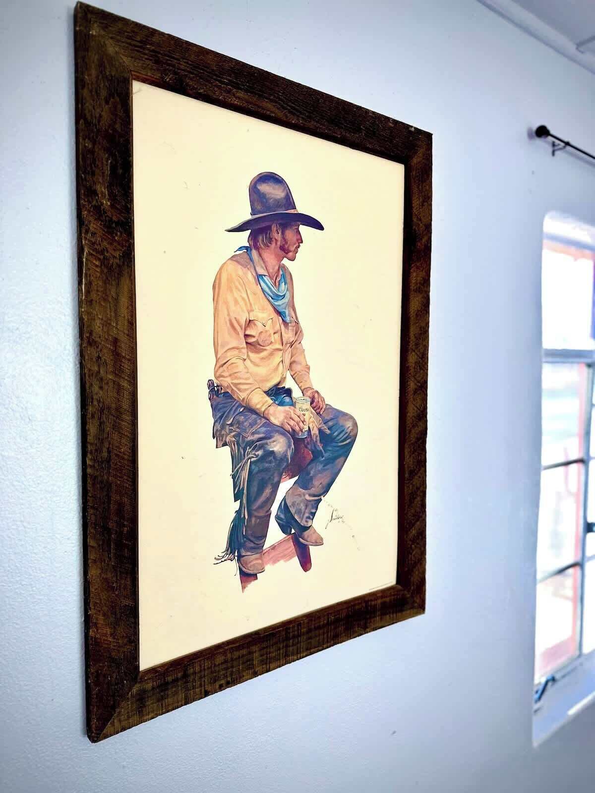 A framed painting of a person sitting on a stool, holding a can.