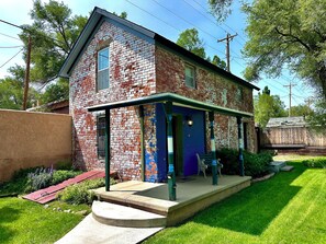 Une maison à deux étages, construite en briques, avec un porche et une porte bleue.