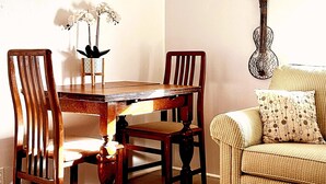 A dining area with a wooden table and chairs, a vase with flowers, and a guitar wall art piece. - 1890s Carriage House \ Walk To Downtown (Raton)
