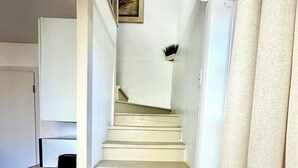 A staircase leading to a landing with a small plant on the wall. - 1890s Carriage House \ Walk To Downtown (Raton)