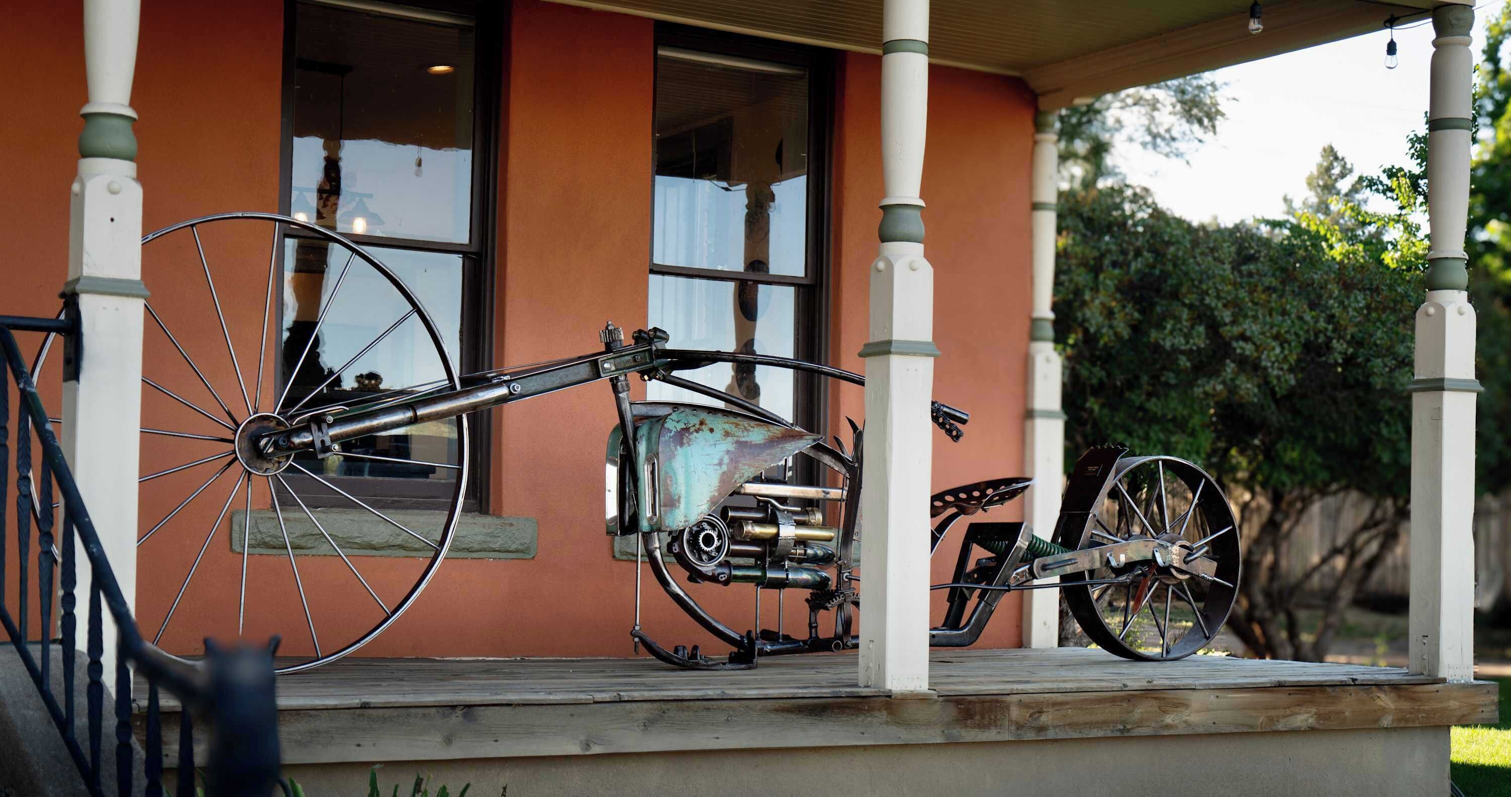 A porch with two bicycles and a motorcycle parked.