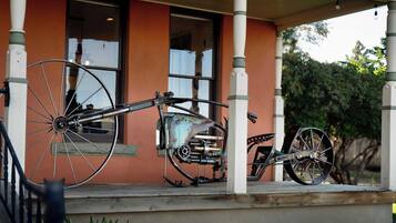 A porch with two bicycles and a motorcycle parked.
