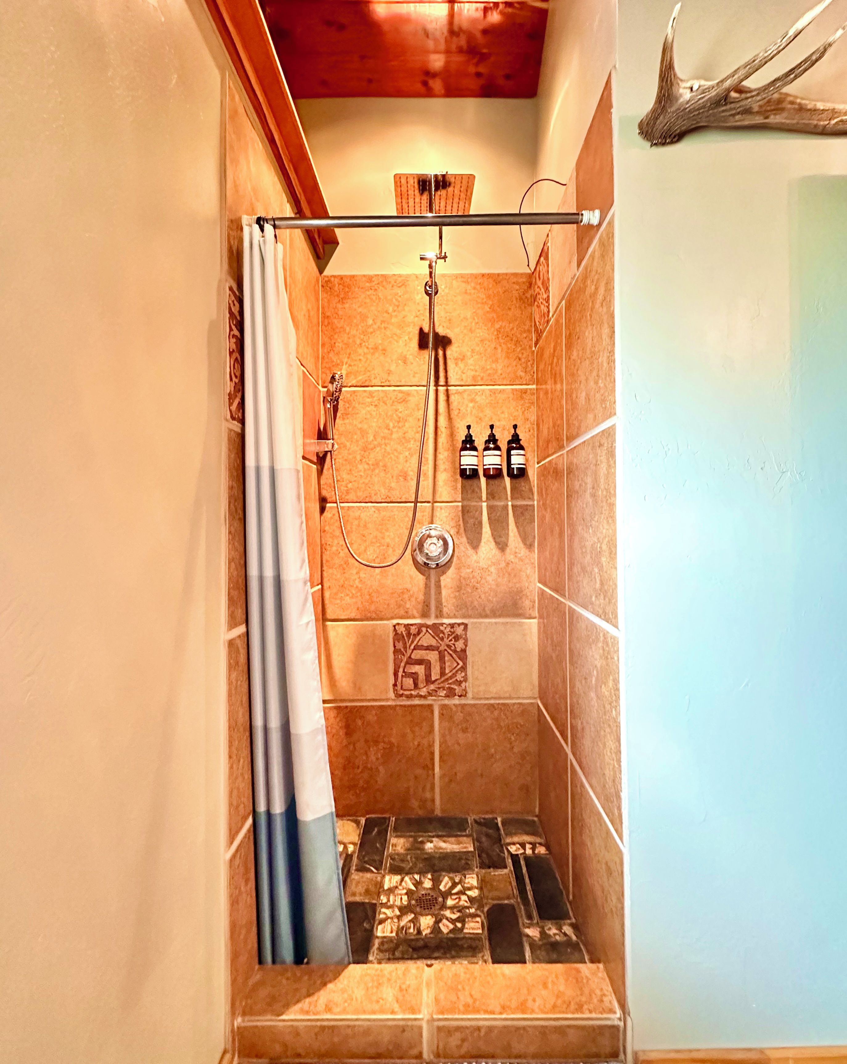 A shower with a curtain, a towel rack, and a showerhead.