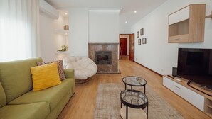 A modern living room with a sofa, a fireplace, a TV, and a dining area. - City Center Grand SEA View Terrace by Vacationy (Porto)