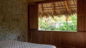 A room with a bed, a window with a view of greenery, and wooden walls. - Utopia Tiny Beach House

 (cozoaltepec tonameca)