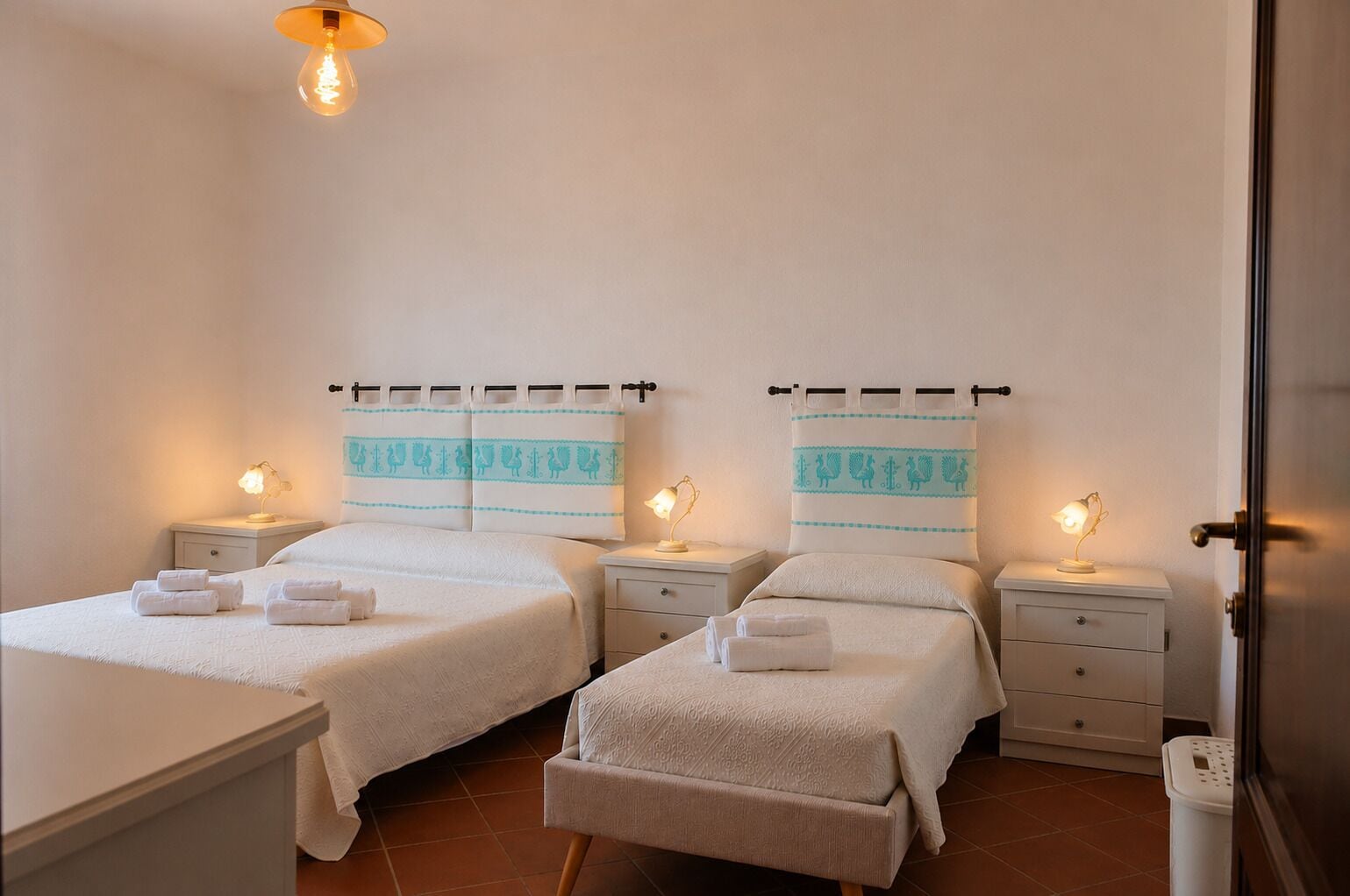 A hotel room with two beds, nightstands, and a door.