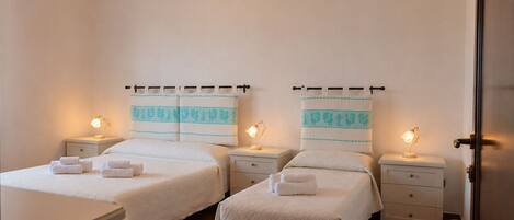 A hotel room with two beds, nightstands, and a door.