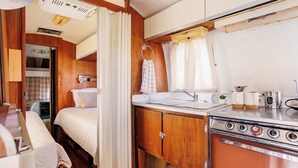 Un intérieur de camping-car compact comprenant un coin cuisine, un lit et une salle de bain.