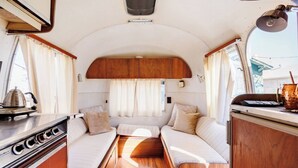 Un intérieur de camping-car compact comprenant un coin cuisine, un espace repas et un coin nuit.