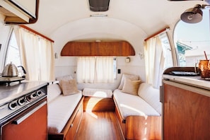 Un intérieur de camping-car compact comprenant un coin cuisine, un espace repas et un coin nuit.