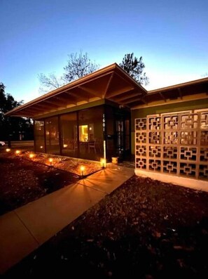 Un bâtiment moderne doté d’une façade en verre, d’un toit en bois et d’un mur orné de motifs.