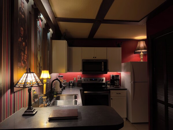 Una cocina con armarios blancos, un microondas, una cafetera y un lavabo.