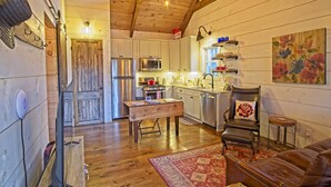 A cozy cabin interior with wooden walls, a dining area, a kitchen with modern appliances, and a comfortable seating area. - Vineyard Waterfall Cabin+Free Tasting  on Turkey Creek (Ellijay)