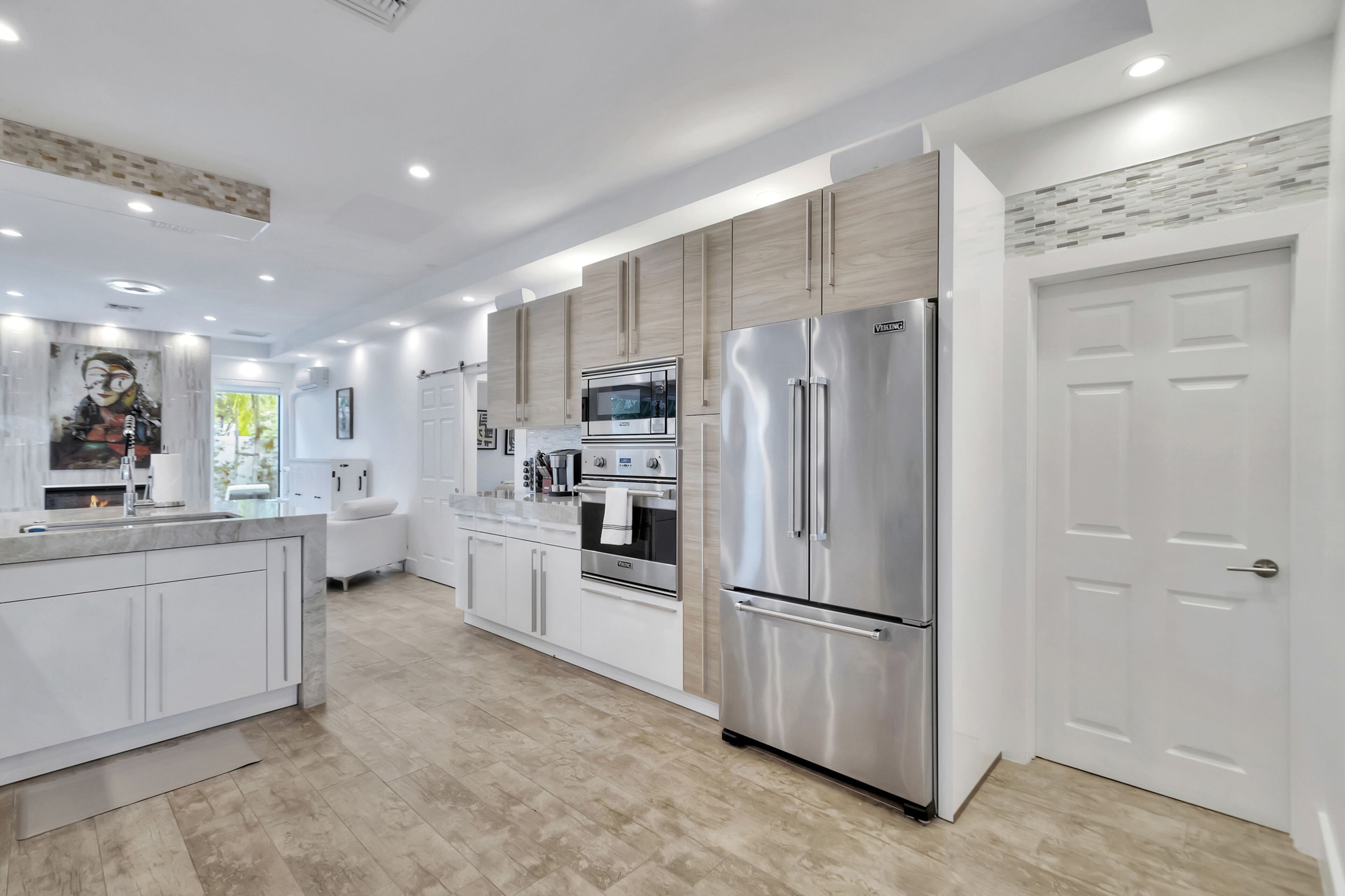 A modern kitchen with white cabinetry, stainless steel appliances, and a large island.