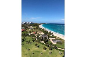 Vue aérienne d’une propriété située sur la côte, avec une plage, une grande maison et plusieurs bateaux en arrière-plan.
