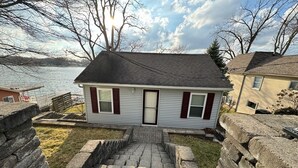 Une maison avec un escalier en pierre menant à la porte d’entrée, située au bord d’un plan d’eau.