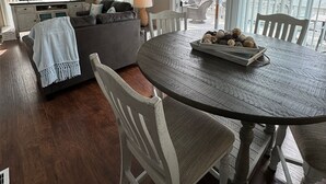 Un coin repas avec une table ronde en bois, des chaises blanches et un lustre.