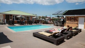 A pool area with lounge chairs and a restaurant named "Mok Restaurant & Bar".