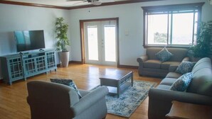 Ein Wohnzimmer mit Fernseher, zwei Sofas, einem Couchtisch und einer Topfpflanze.