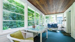 A sunroom with large windows, a glass table, wicker chairs, and a blue sofa. - Four Night Min! Lakeside Home With 800 Feet Of Association Beach! (Lakeside)