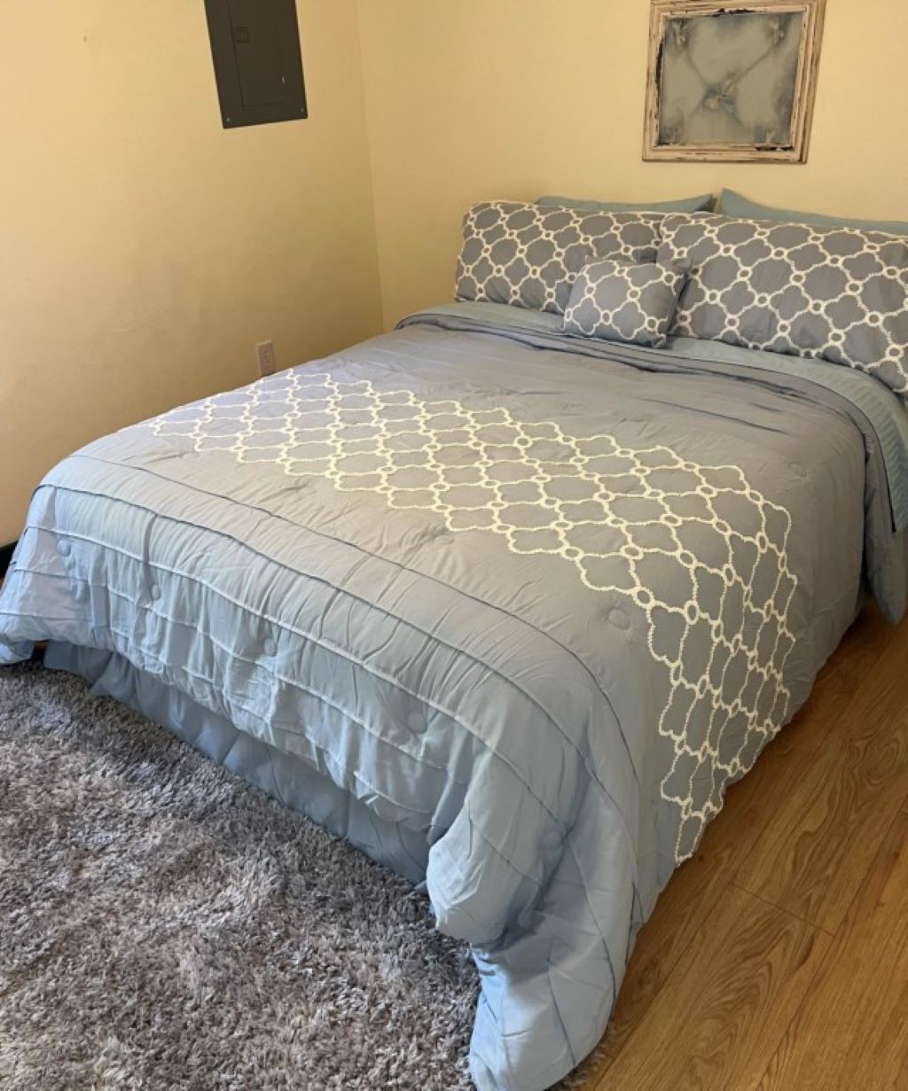 Ein Schlafzimmer mit einem Bett, einem Teppich und einem Bild an der Wand.