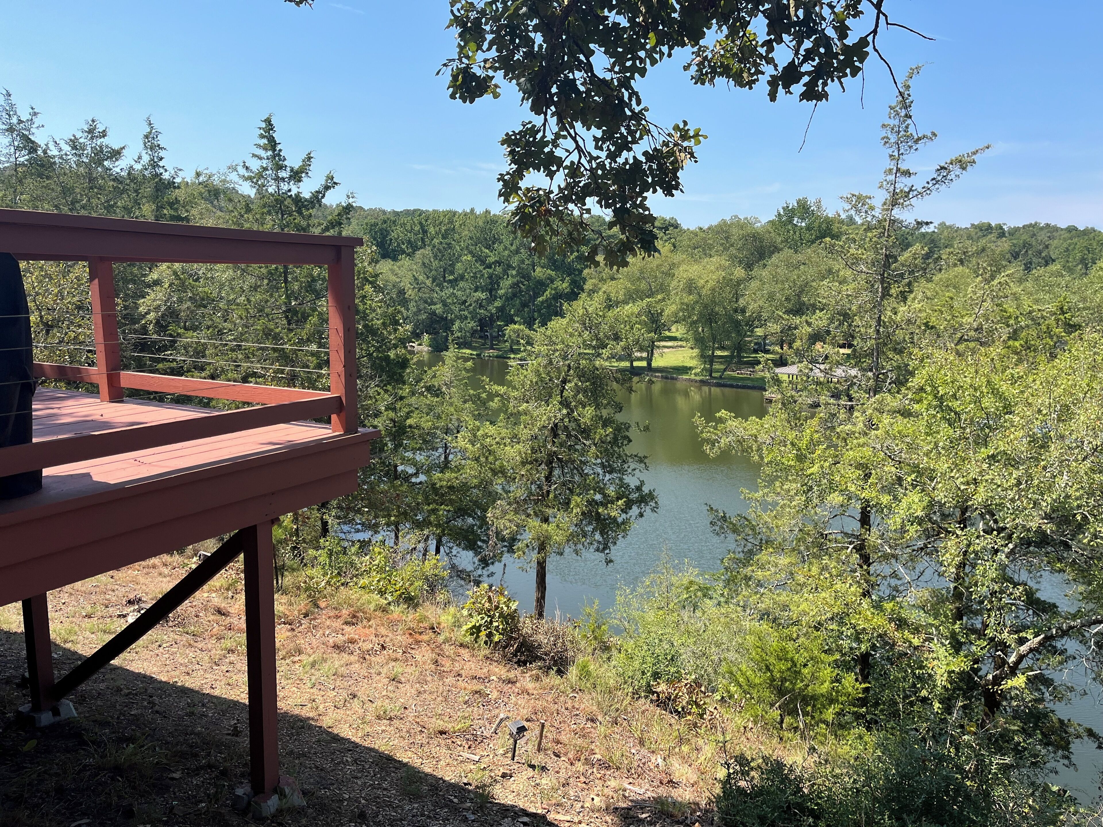 A wooden deck overlooking a lake surrounded by trees.