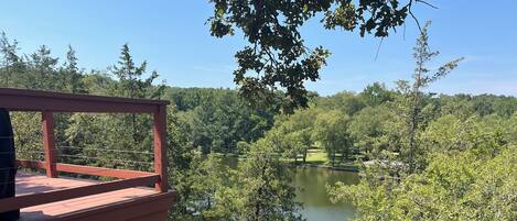 A wooden deck overlooking a lake surrounded by trees.