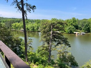 Ein See, umgeben von dichtem Wald und einer Holzterrasse.