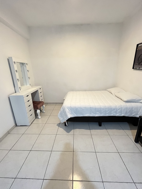 Un dormitorio con cama, cómoda con cajones, espejo e imagen colgada en la pared.