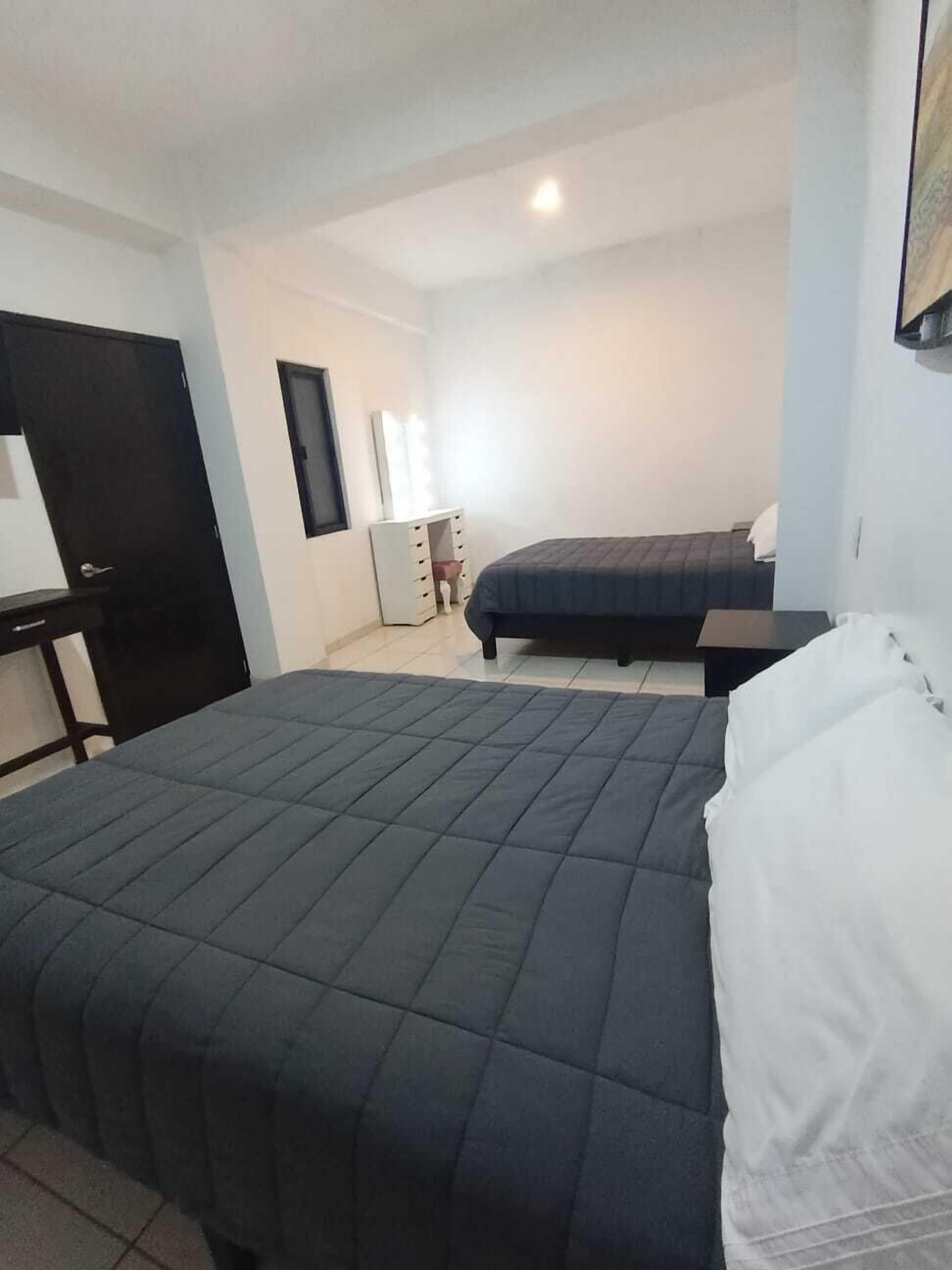 Un dormitorio con cama, escritorio y cómoda.
