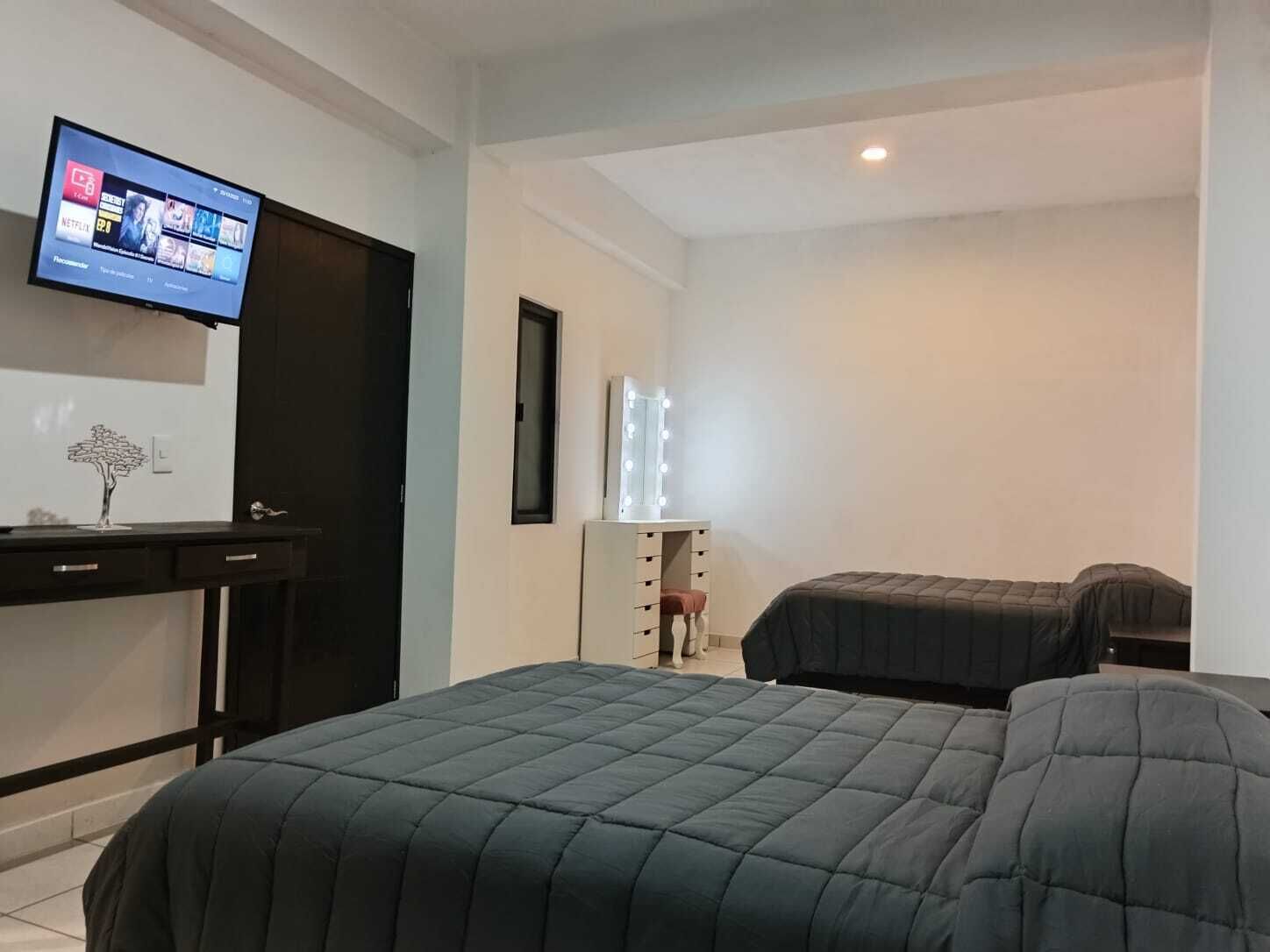 Habitación de hotel con dos camas, un escritorio, un televisor y un tocador con luces.