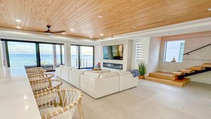 A spacious living area with a large TV, a sofa, and a dining area with wicker chairs. - 5 bed/4 bath Ocean side, right outside of Tavernier Creek Mile Marker 91 (Tavernier)