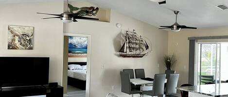A modern living room with a sofa, TV, and ceiling fans.