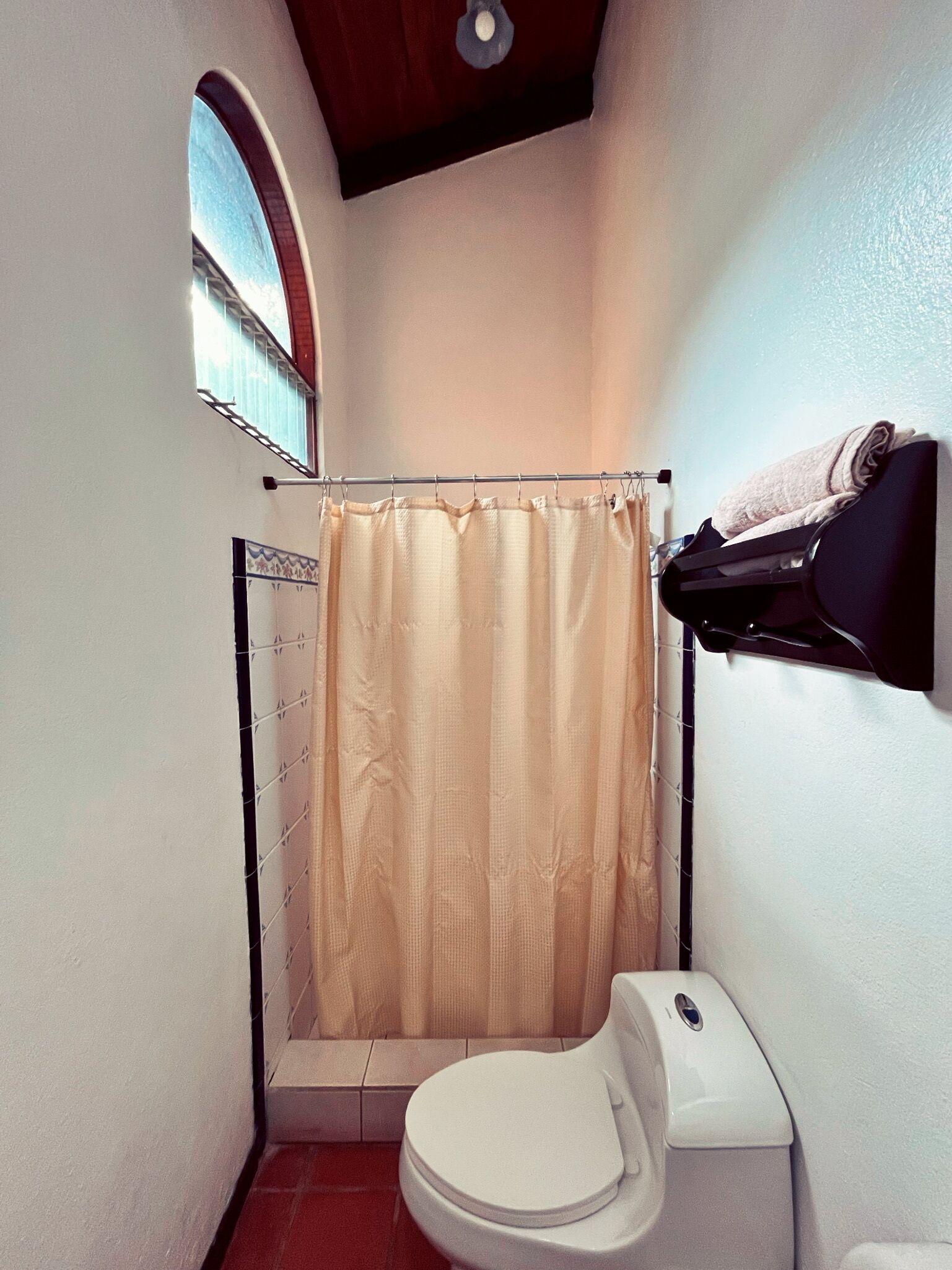 Een kleine badkamer met toilet, douchegordijn en een handdoekhouder.