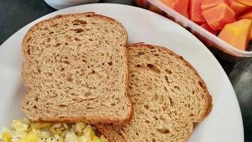A breakfast plate with toast, scrambled eggs, and diced fruit.