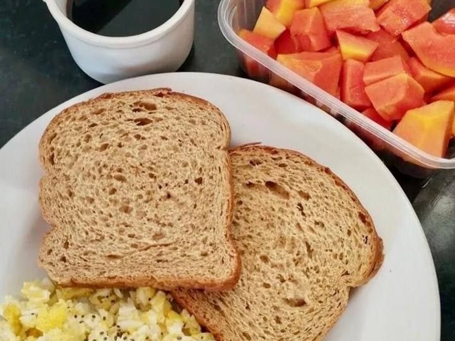 A breakfast plate with toast, scrambled eggs, and diced fruit.