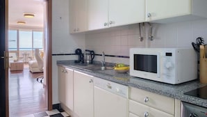 Cozinha com armários brancos, bancada de granito, micro-ondas e cafeteira.