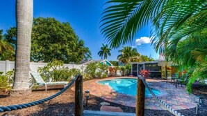 A backyard with a swimming pool, wooden deck, and lounge chairs.
