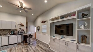 A spacious kitchen with a large island, white cabinetry, and a ceiling fan.