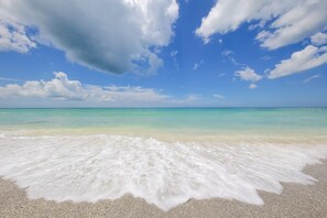 Een strand met helder turquoise water en een zandkust.