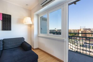 Ein Zimmer mit einer Couch, einem Fenster mit Stadtblick und einer Klimaanlage.