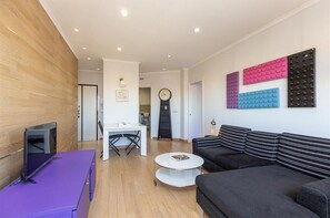 Ein modernes Wohnzimmer mit einer Couch, einem Couchtisch, einem Fernseher auf einem Schrank und einer Wand mit bunten Paneelen.