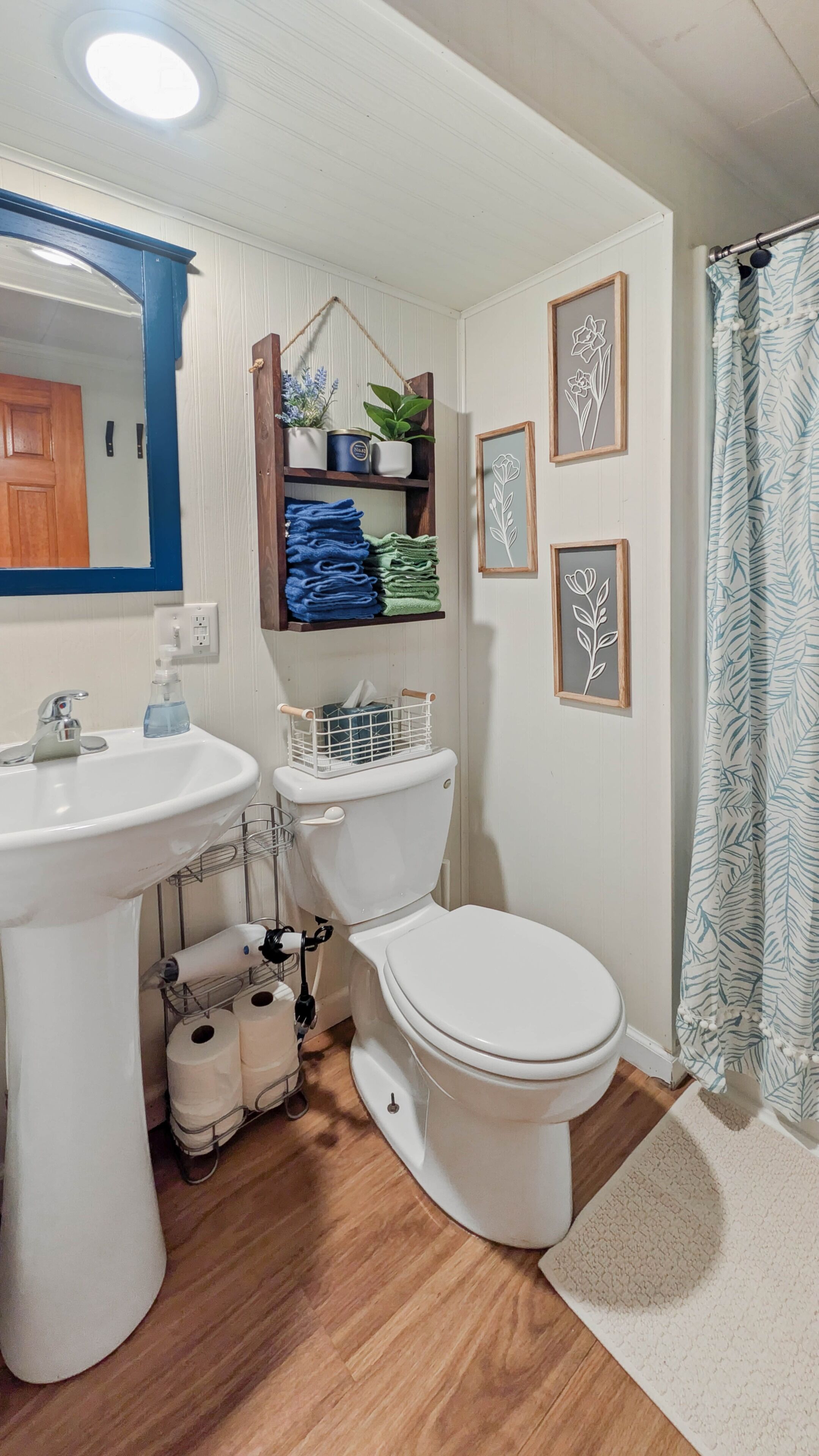 A bathroom with a pedestal sink, toilet, and a shower curtain.