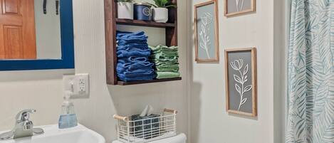 A bathroom with a pedestal sink, toilet, and a shower curtain.