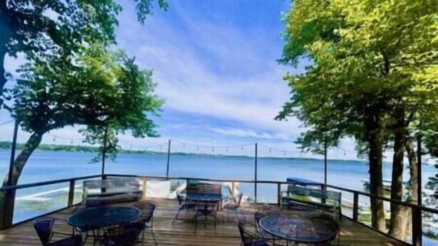 A wooden deck with tables and chairs overlooking a body of water.