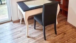 Una stanza con un tavolo da biliardo, una sedia nera, pavimento in legno, una libreria e un quadro appeso al muro.