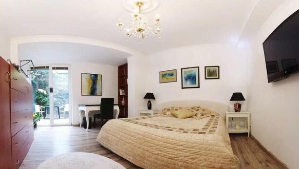 Una camera da letto con un letto grande, una scrivania, una sedia, un lampadario e opere d'arte alle pareti.