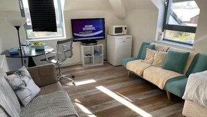 A cozy room with a sofa, a small TV, a desk, and a microwave. - Home Sweet Home: Whole Apartment 15mins to Central

 (Wembley)