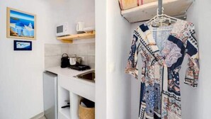 Une cuisine moderne avec des meubles blancs, un four à micro-ondes et un étendoir suspendu où sont accrochés des vêtements à motifs.