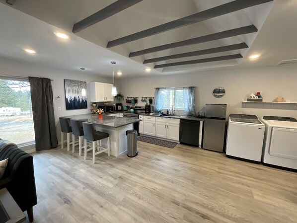 Een moderne keuken met een centraal eiland, witte kasten en roestvrijstalen apparatuur.